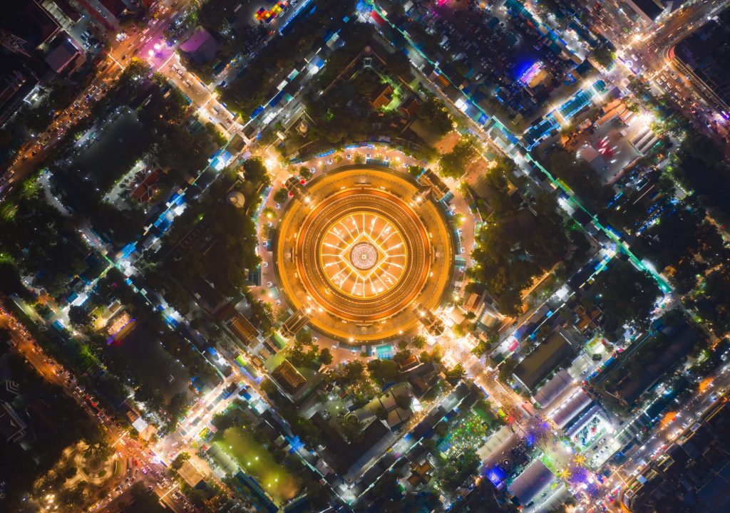 Aerial top view of Phra Pathommachedi temple at night. The golden buddhist pagoda with residential houses, urban city of Nakorn Pathom district, Thailand. Holy Thai architecture.